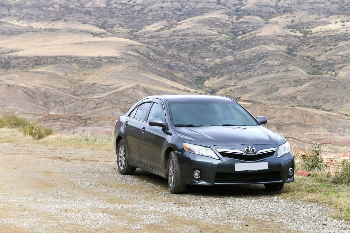 Japanese saloon car Toyota Camry at the background of a mountains.