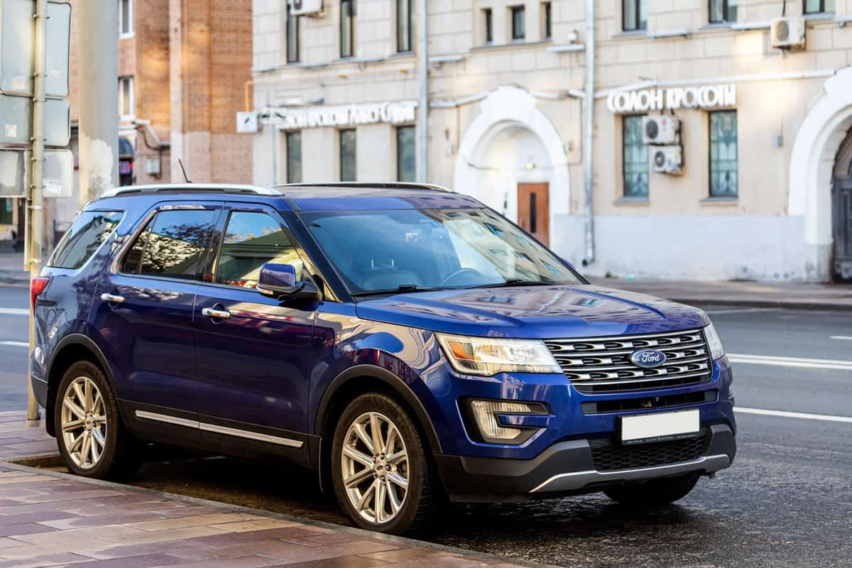  blue Ford Explorer is parked on the street on a warm autumn day against the backdrop of a parking