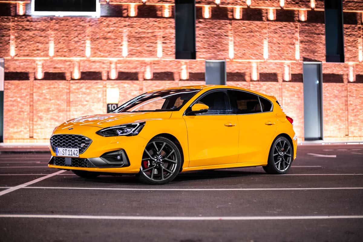 photo of a glossy sport yellow hatchback car on the middle of the street on night time
