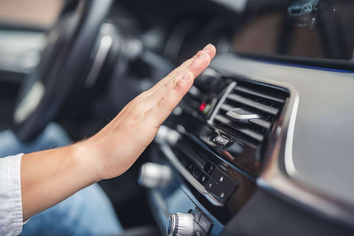 photo of a man hand on front of the aircon vents of the car interior dashboard