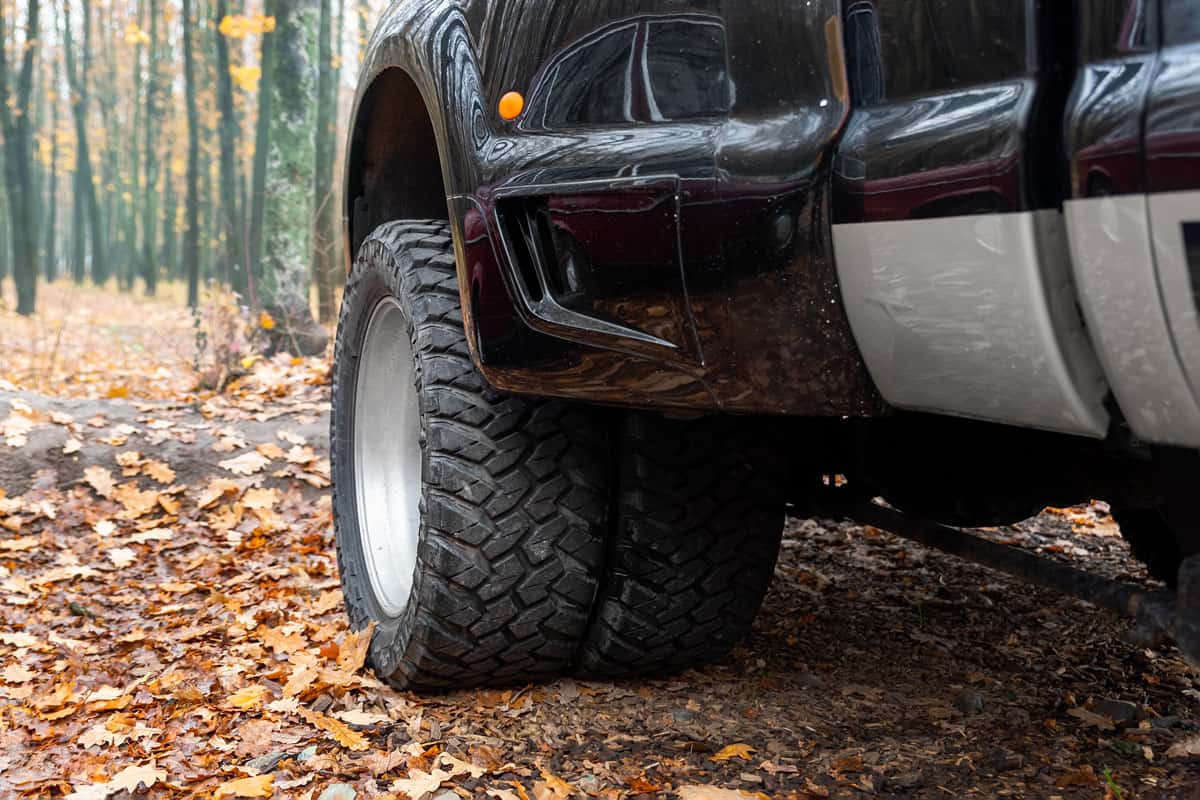 pov view of dual twin offroad performance wheel of super heavy duty pickup truck car at autumn forest countrys