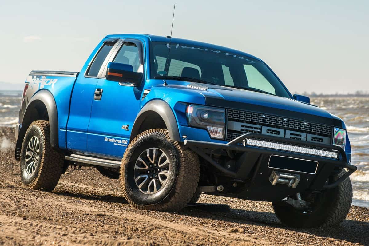A huge blue colored Ford F150 trekking at a dirt road