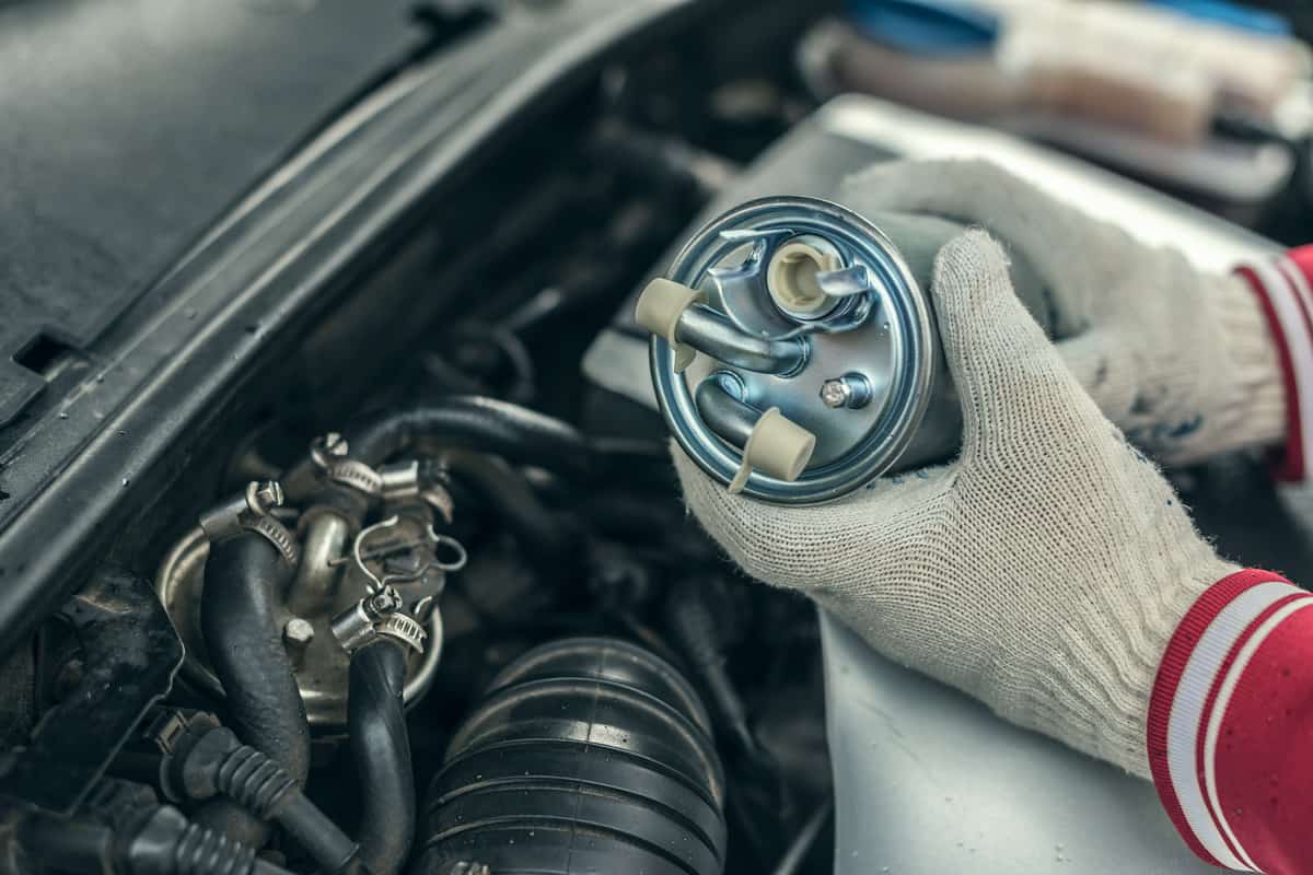 Auto mechanic replaces a car's fuel filter.