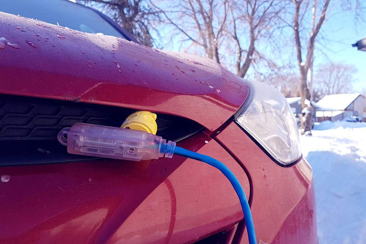Block heater cable, plugged into a vehicle parked in a snowy winter driveway.