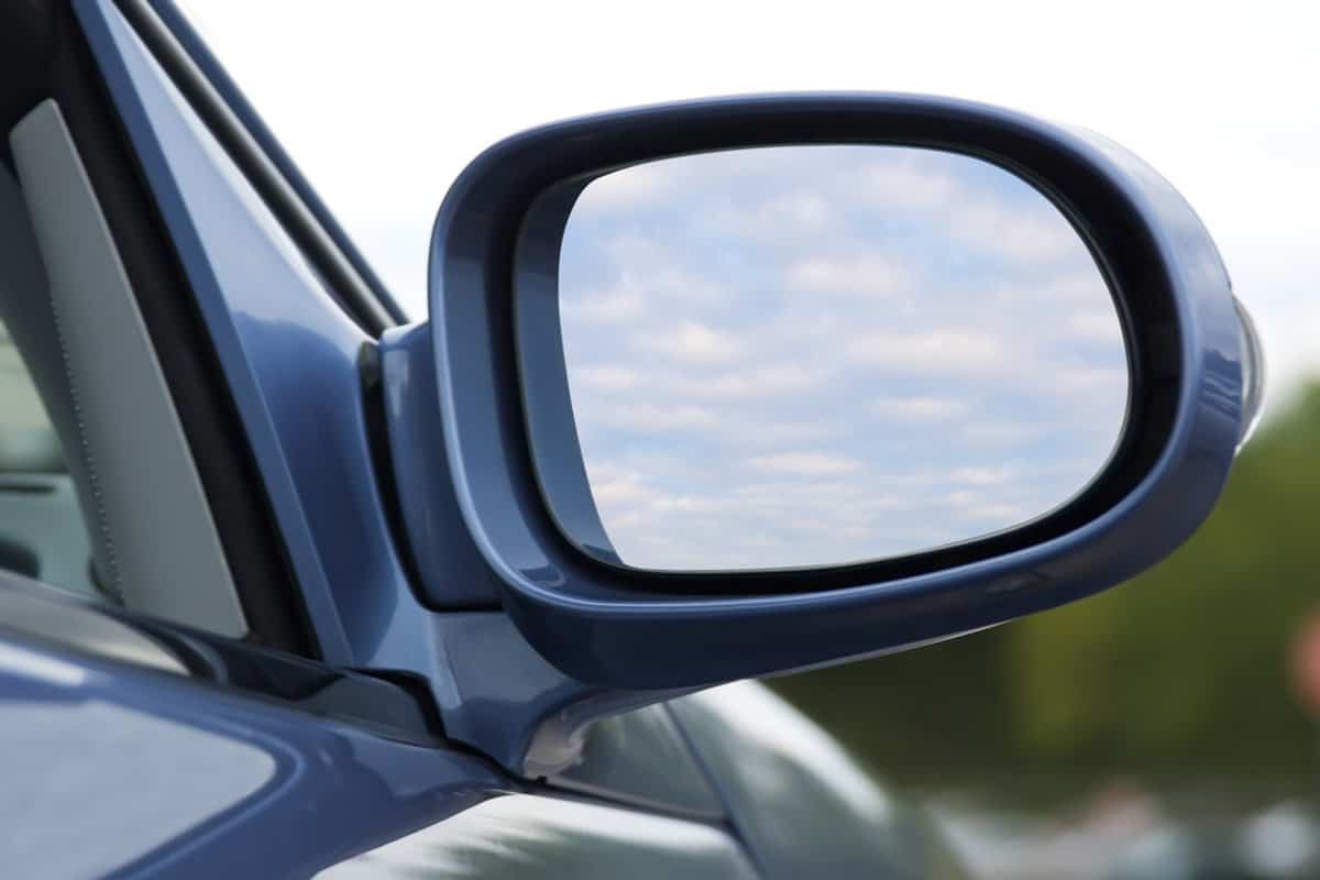 Close up of side mirror of a pearl blue luxury convertible reflecting clouds in the sky. Includes clipping path for what appears inside the mirror.