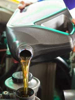 Car mechanic replacing and pouring fresh oil into engine at maintenance repair service station - How Long Does It Take To Change Oil And Rotate Tires