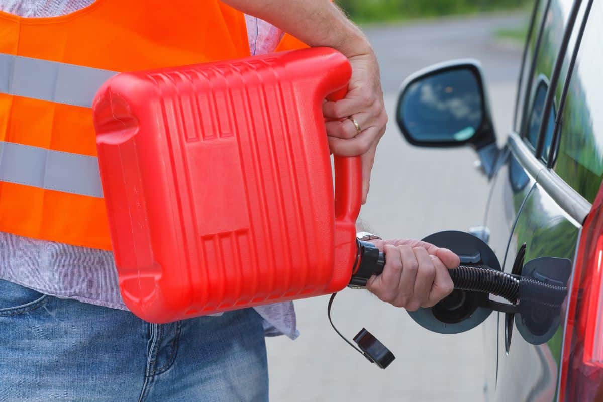 Driver fills the fuel in an empty car tank from red canister on the side of the road