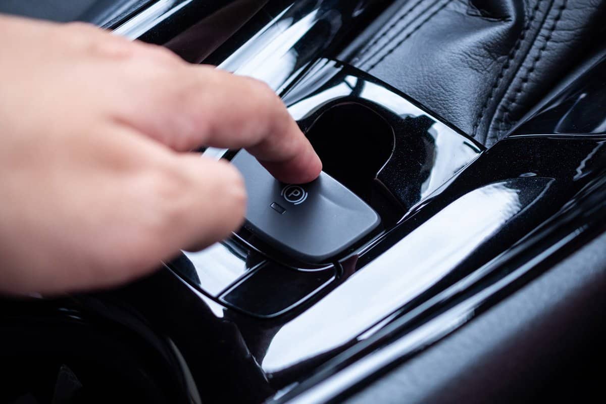 Hand push on electronic handbrake button in luxury modern car