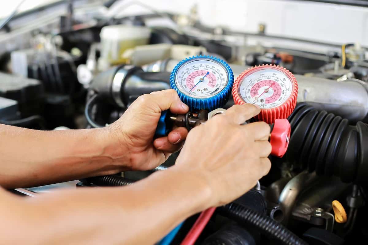 Mechanic checking the freon level of a car air conditioning system