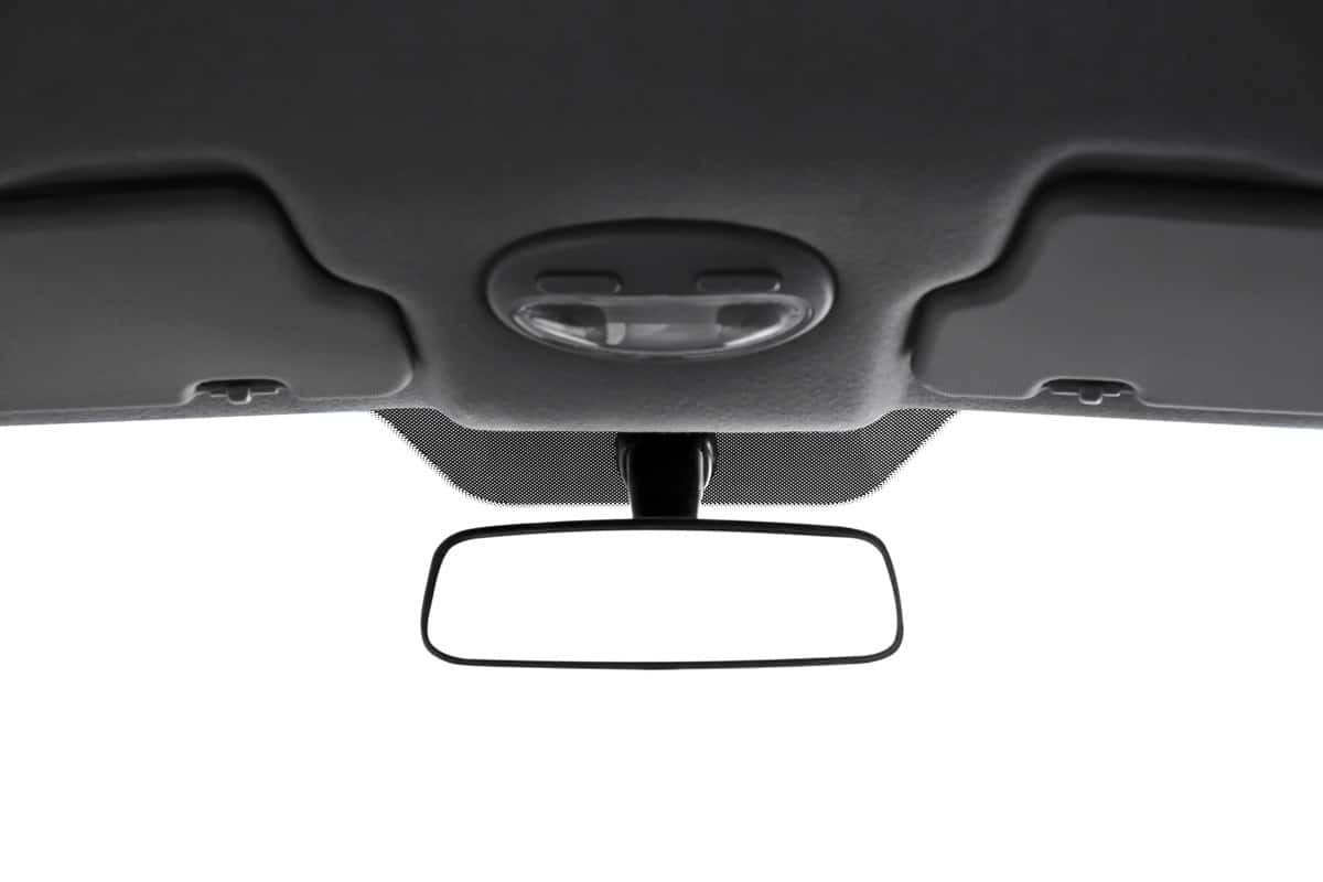 Modern rear view mirror and part of car ceiling on white background