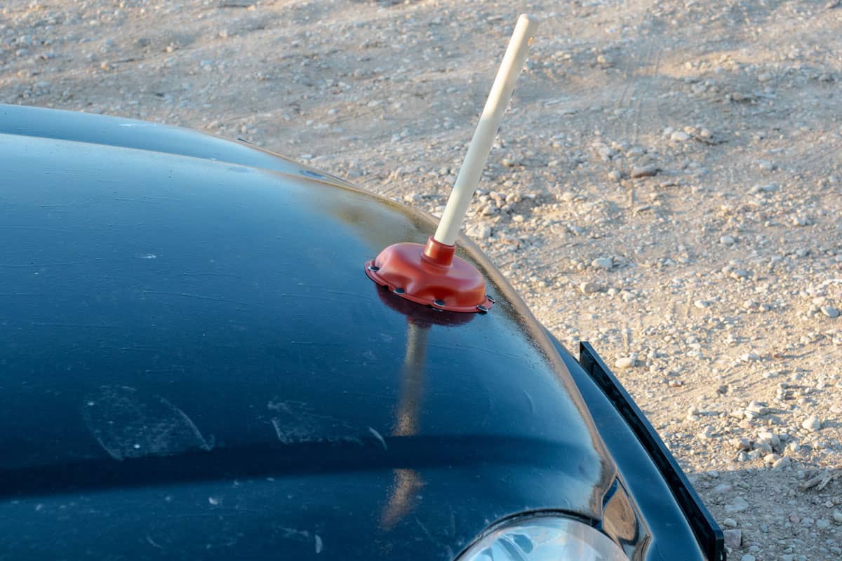Sink plunger on the hood of the car. Unusual use of the sink plunger.