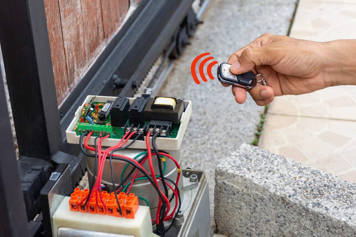 Technician man hand using remote control, testing and checking the functional of auto door. Maintenance and repairing automatic gate concept. service concept.