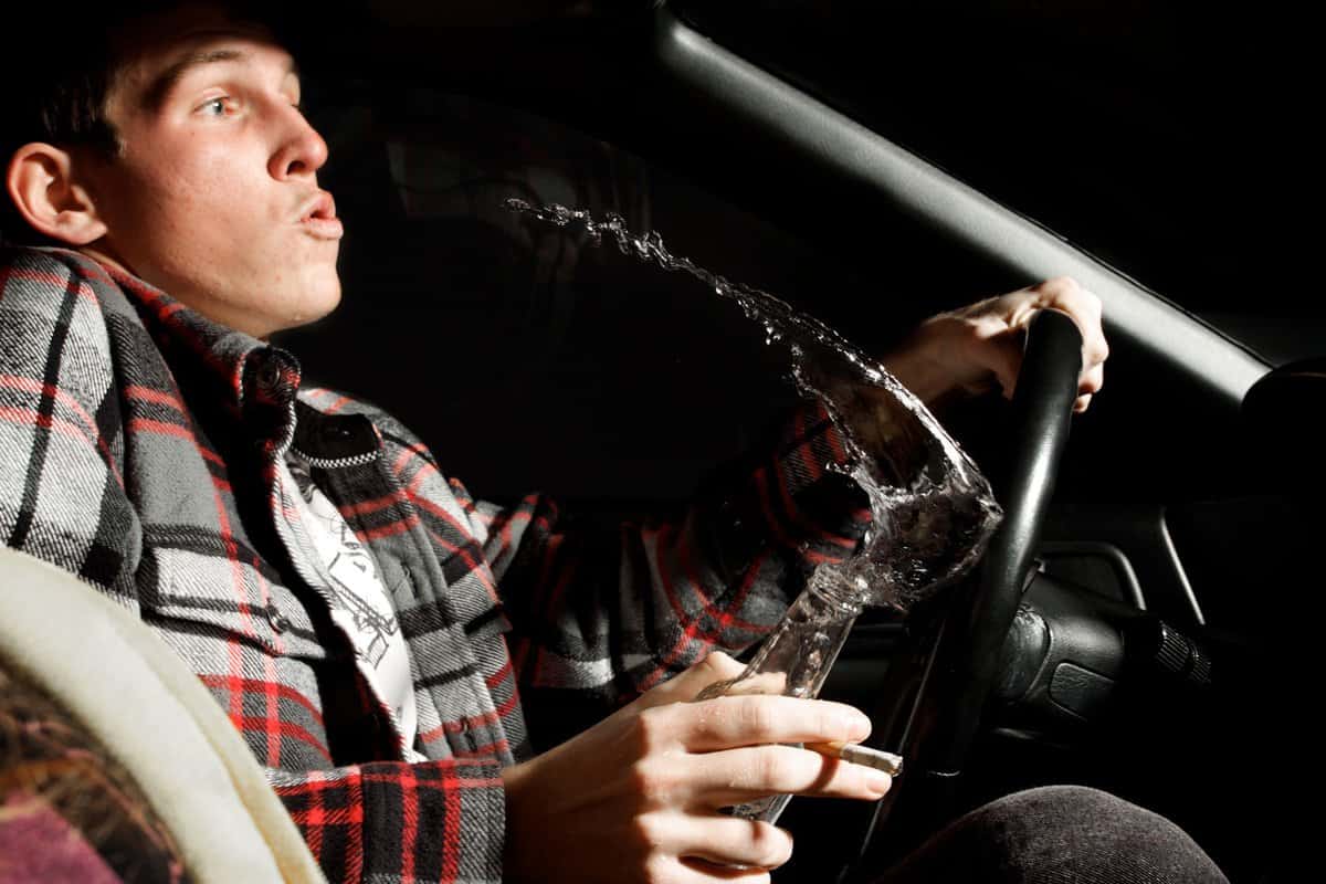 Teenage Boy Drinking Beer and Spilling While Driving Car