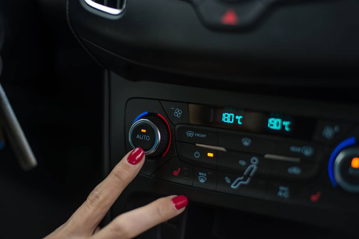 Woman turning on car air condition. Modern car interior