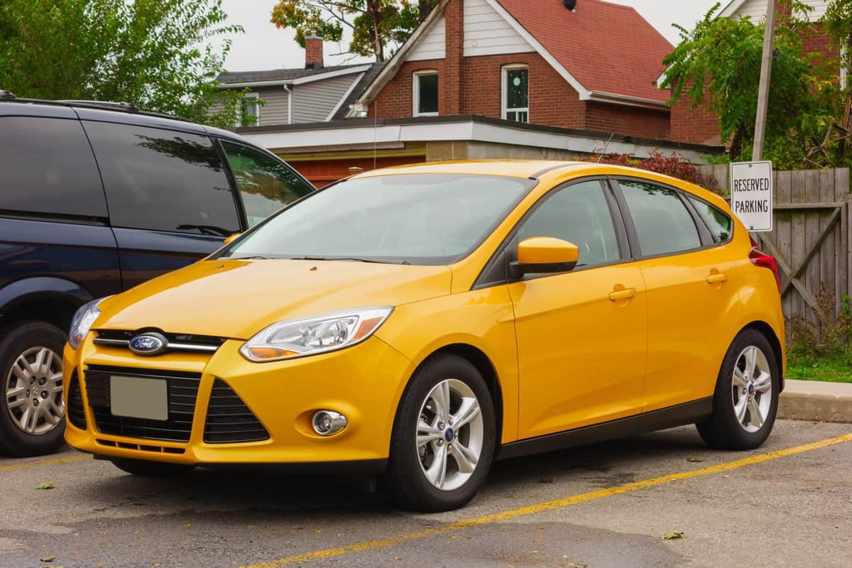 Yellow colored, third generation Ford Focus hatchback parked in a parking lot.