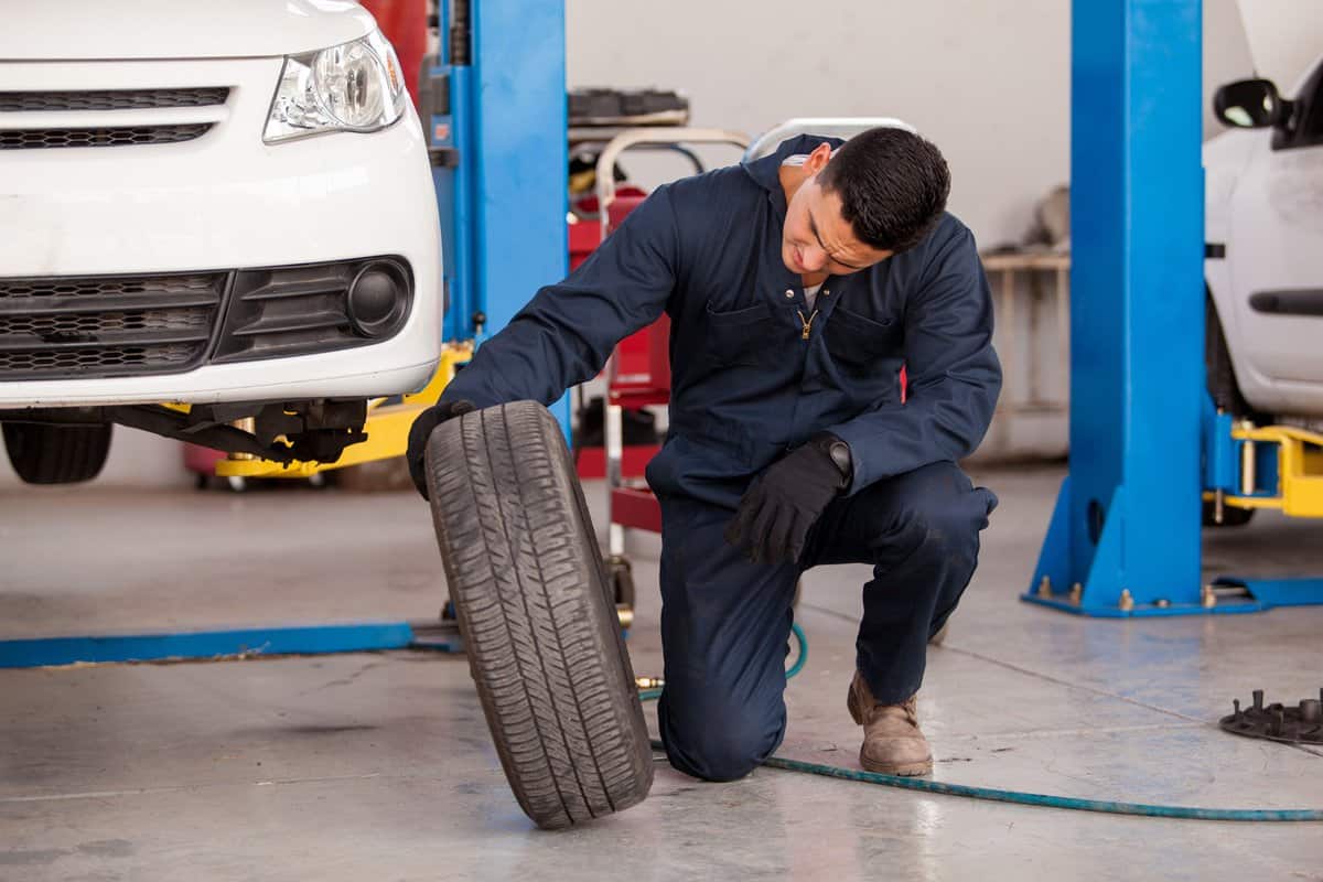 Young mechanic inspecting a car tire at an auto shop