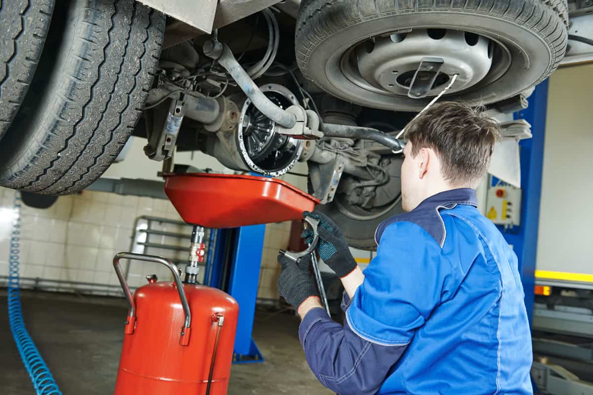 auto repairman mechanic works with rear axle reduction gear of commercial van in car auto repair or maintenance shop service sta