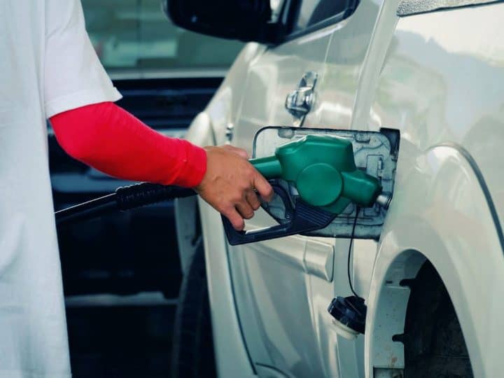 close up worker hand holding nozzle fuel fill oil into car tank at pump gas station, saving money and energy for transport, tr