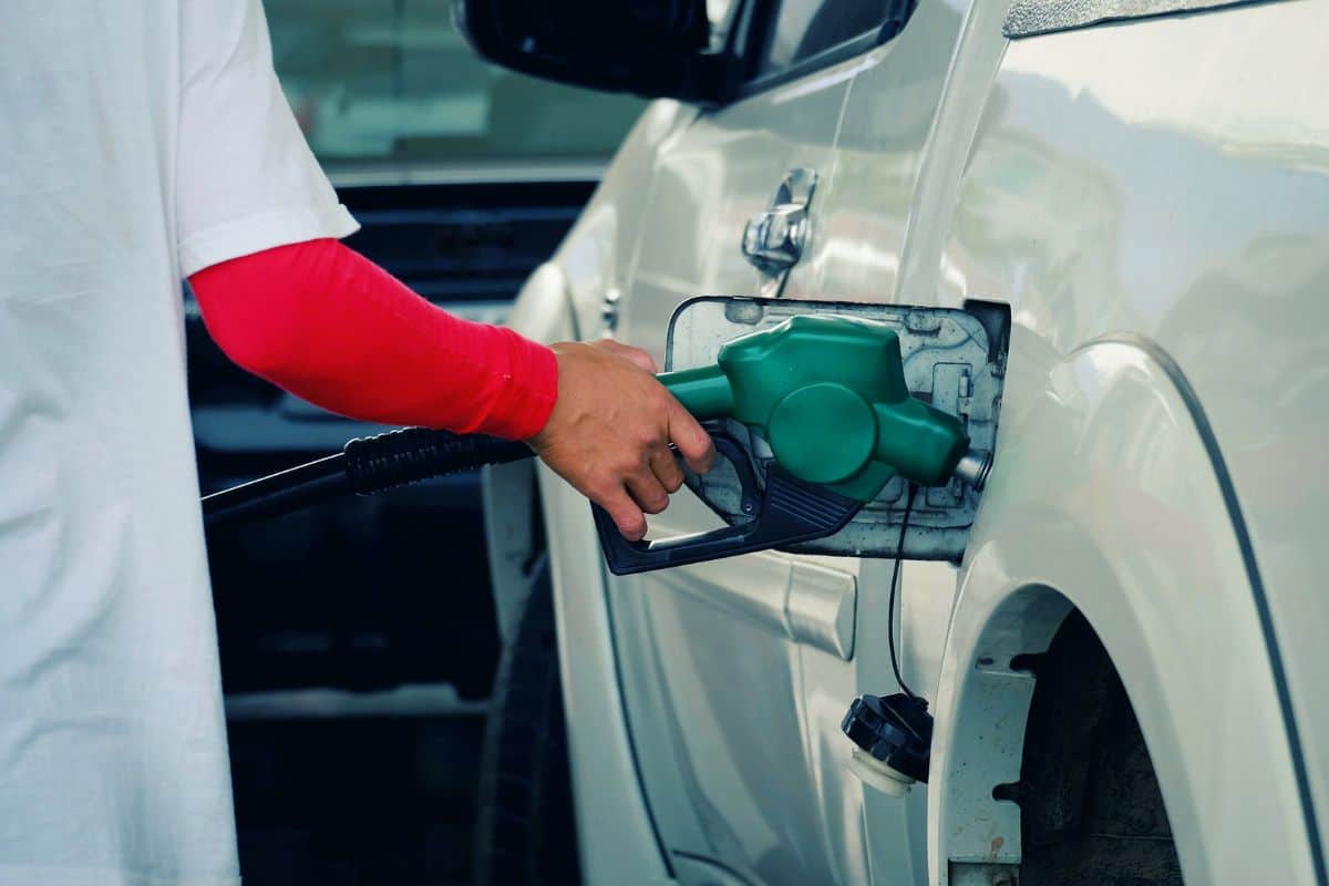 close up worker hand holding nozzle fuel fill oil into car tank at pump gas station, saving money and energy for transport, transportation technology, industry business, vintage tone