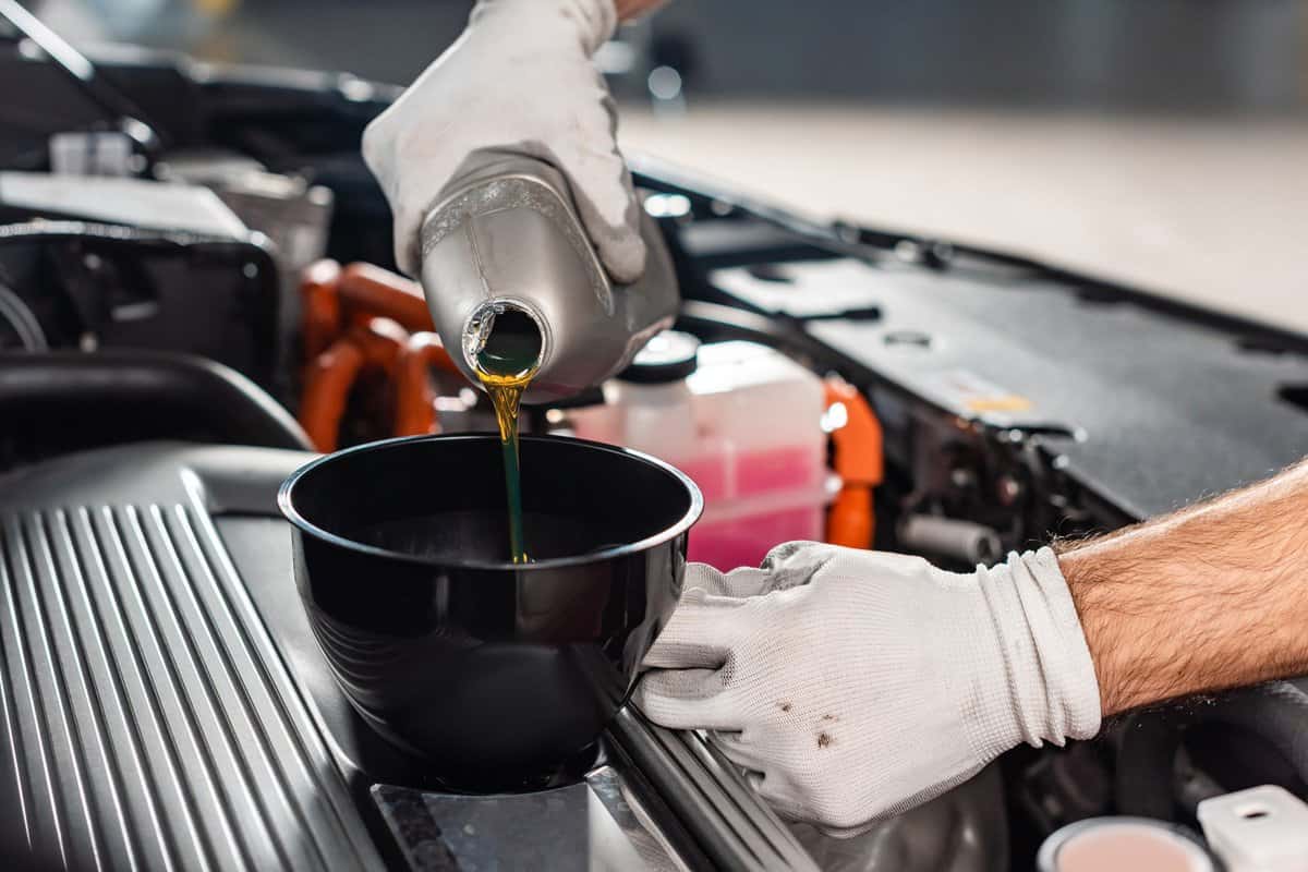 cropped view of mechanic pouring oil to car engine
