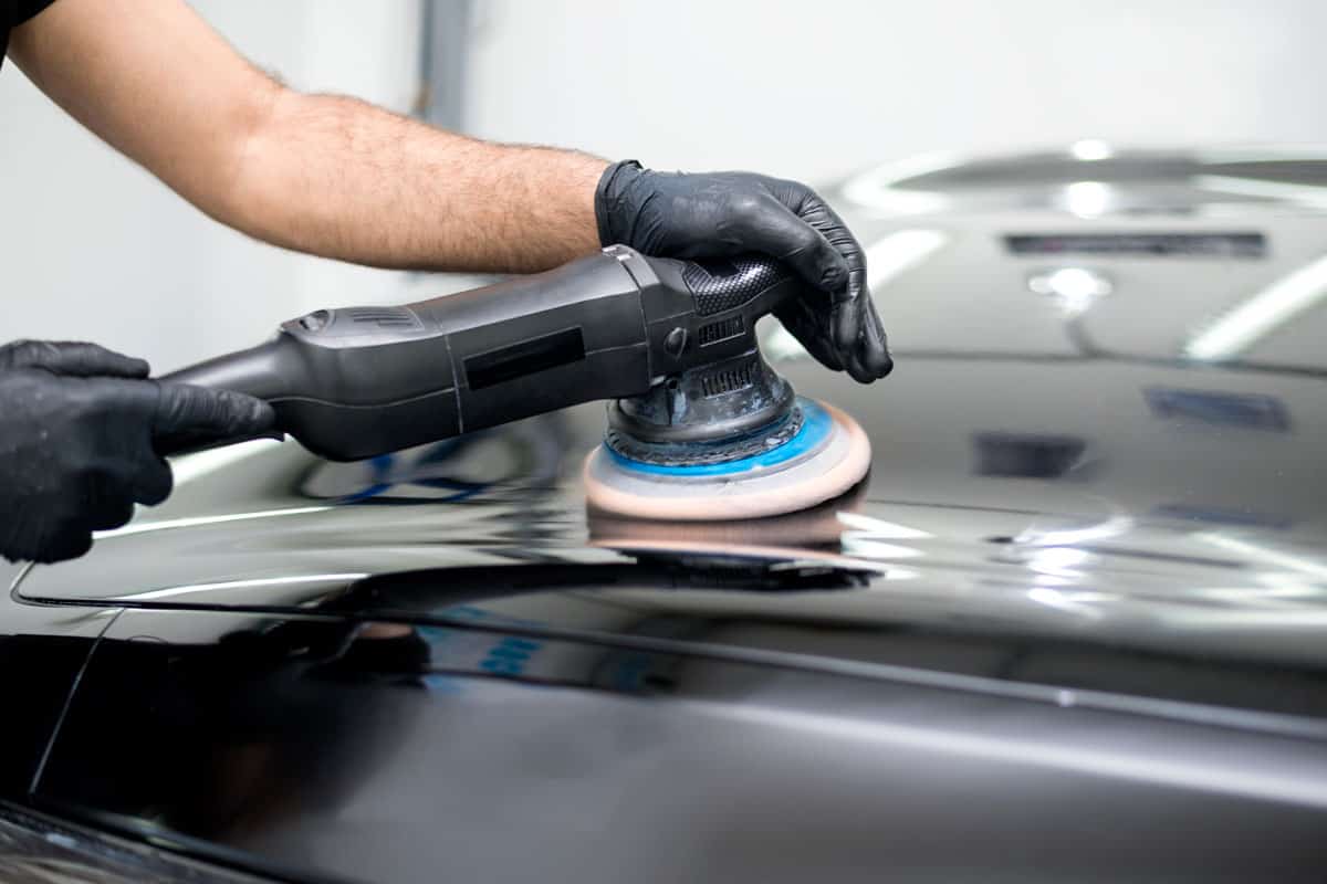 man buffing the black glossy car paint