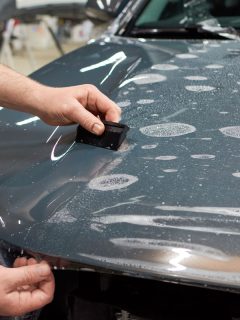 man installing cling film on the hood of the glossy grey car paint, Does Cling Film Damage Car Paint?