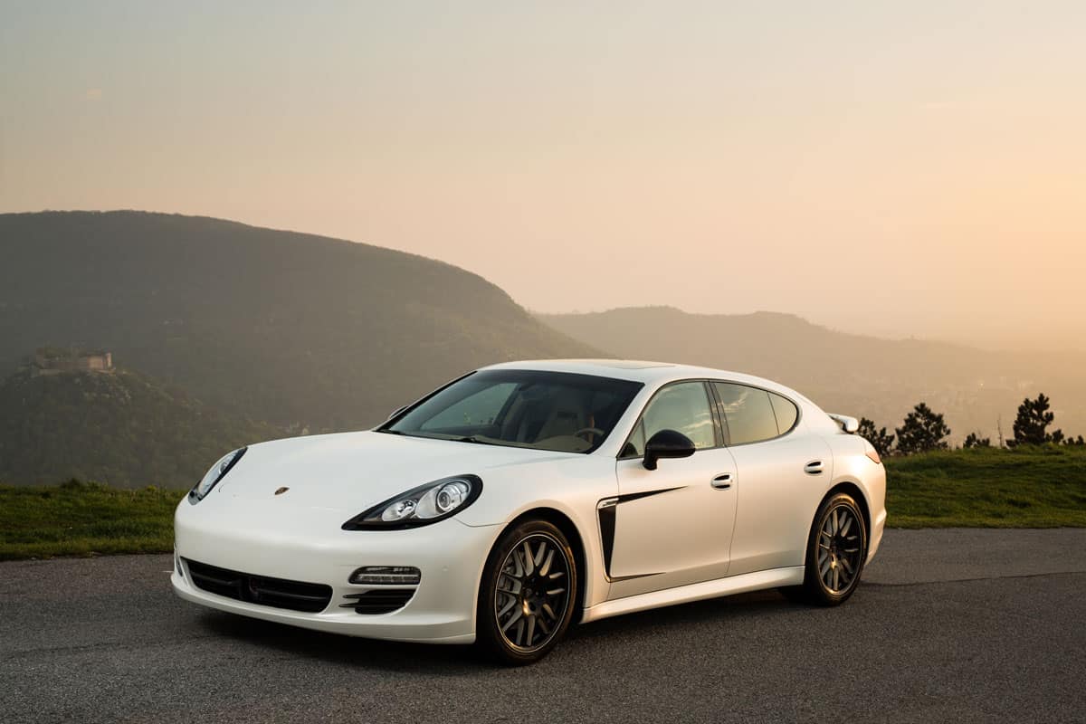 matte pearl white painted porsche on the sun set on the mountain
