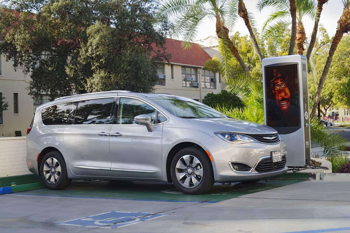 silver Chrysler Pacifica Electric Vehicle charging on a charging station