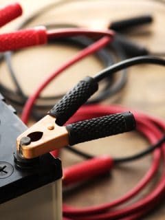 A Car battery with red and black battery Jumper Cables with copper clamps attached to the terminals., Can You Overcharge A Lead Acid Battery?