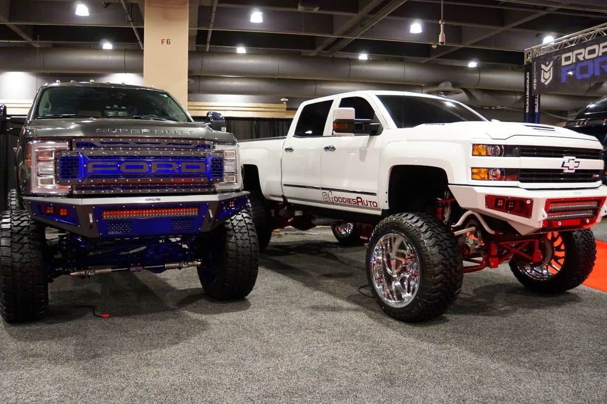 A Chevy and a Ford truck with a suspension lift kit