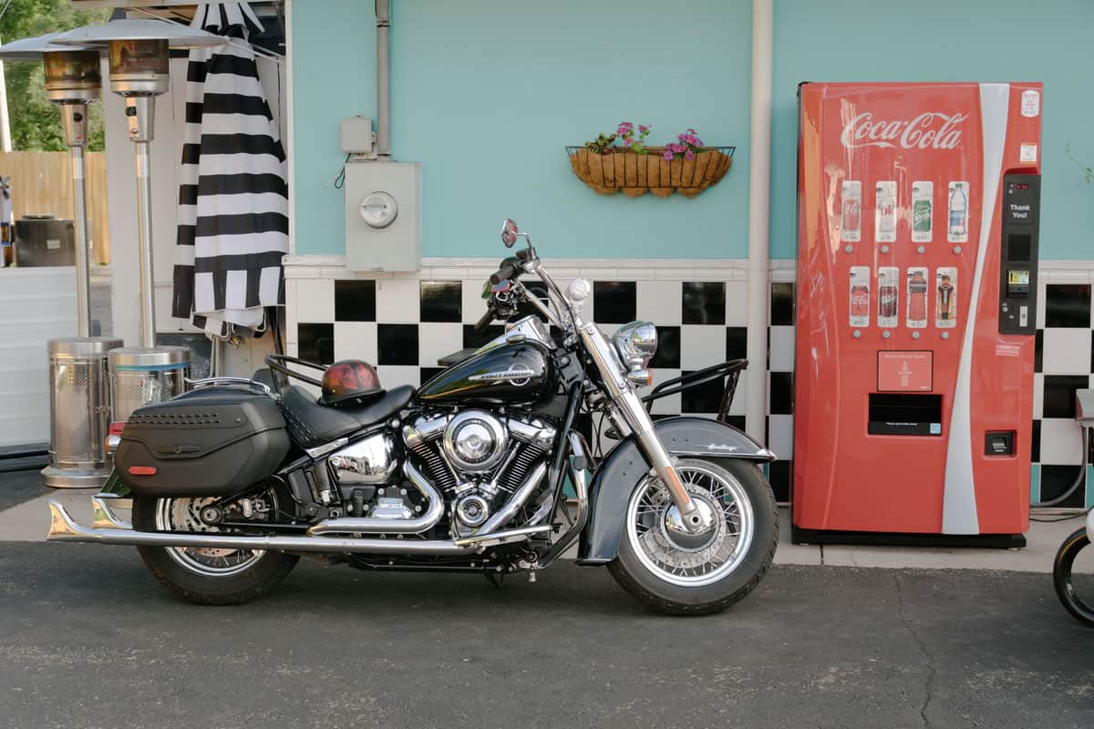 A closeup shot of Harley Davidson motorcycle with modern Coca-Cola machine