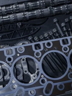 A new cylinder head gasket with various timing parts on a table in a car repair shop, Can A Head Gasket Blow Without Overheating?