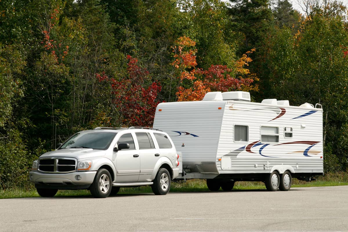 A silver SUV and coordinating tow trailer in a generic autumn scene