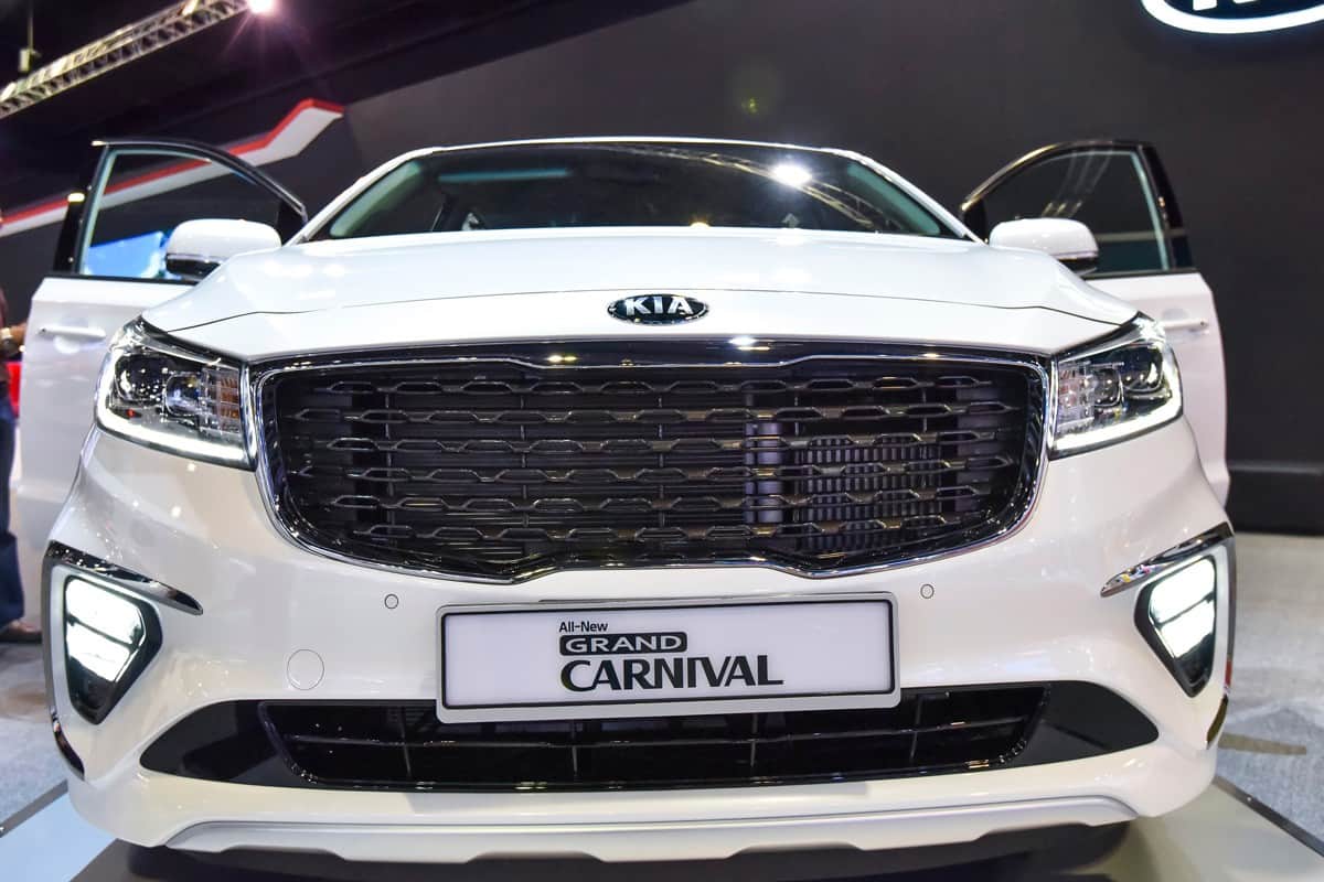 A white Kia Grand Carnival at a car show