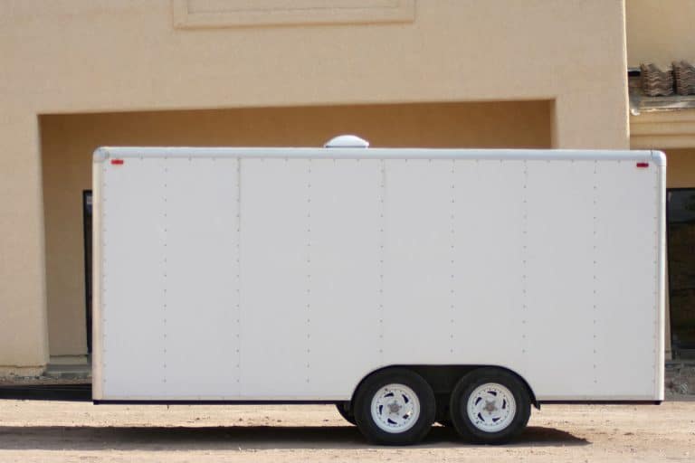 A white trailer parked in a vacant space near a building storage, Are Bigger Tires Better For Trailers?