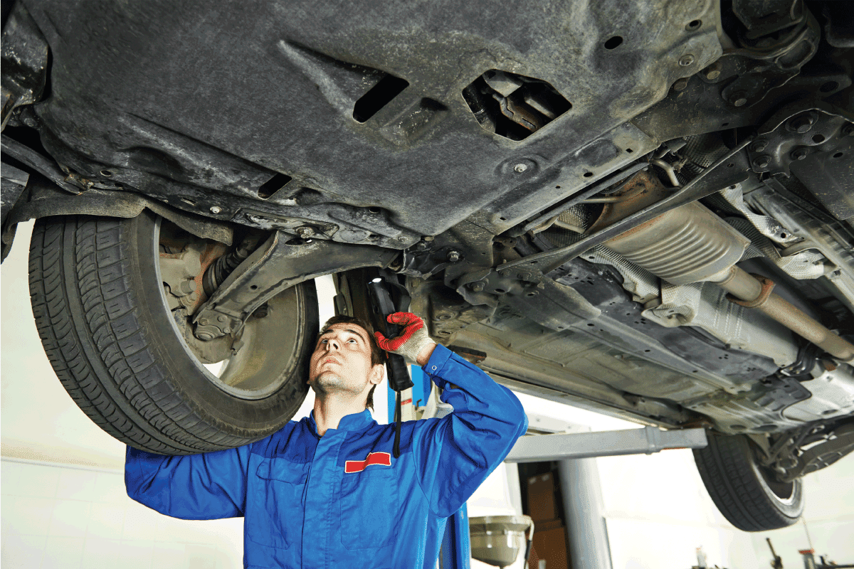 Automobile mechanic inspecting car suspension in service station