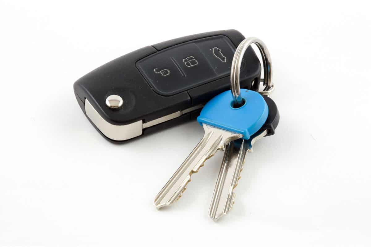Car key fob with house keys on white background
