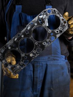 Car mechanic hands in garage with old engine gasket. Concept - Can You Reuse A Head Gasket? Should You