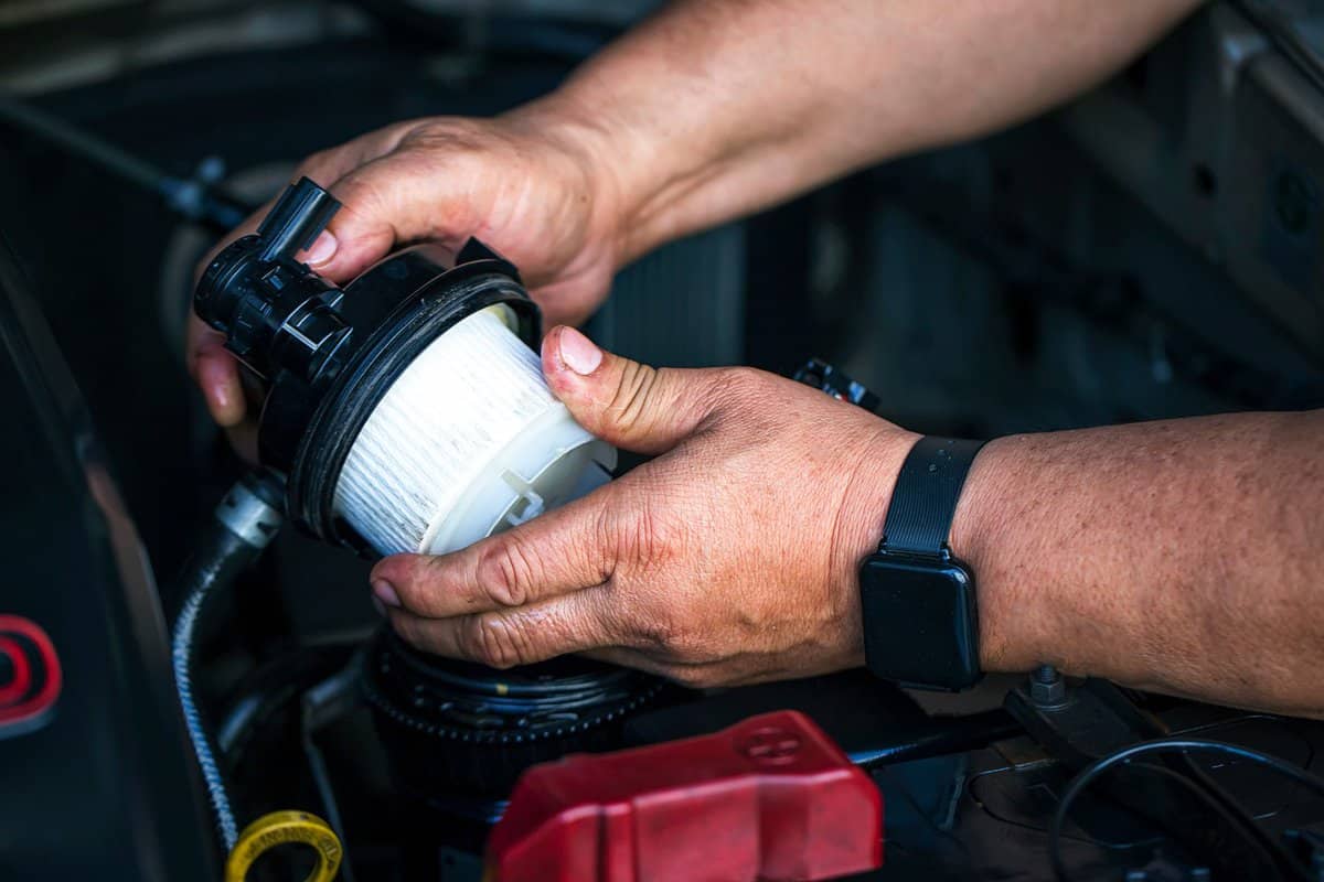 Car mechanic replace the new fuel filter at modern diesel engine. car service or preventive maintenance.