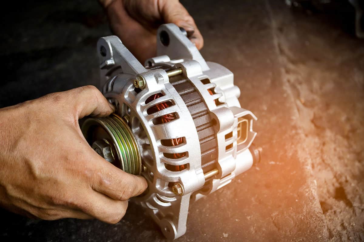 Change new car alternator with hand in the garage or auto repair service center,