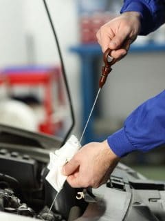Mechanic pouring oil into car at the repair garage. - What Is The Best Oil For Volvo XC90?