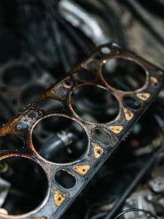Cylinder block and a damage head gasket on the hand of a mechanic, How To Fix A Blown Head Gasket Without Replacing It [Step By Step Guide]