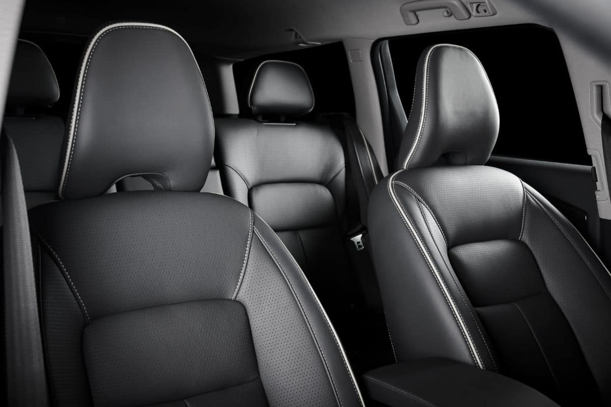 Interior of prestige modern car. Comfortable leather seats. Black perforated leather cockpit with isolated black background.