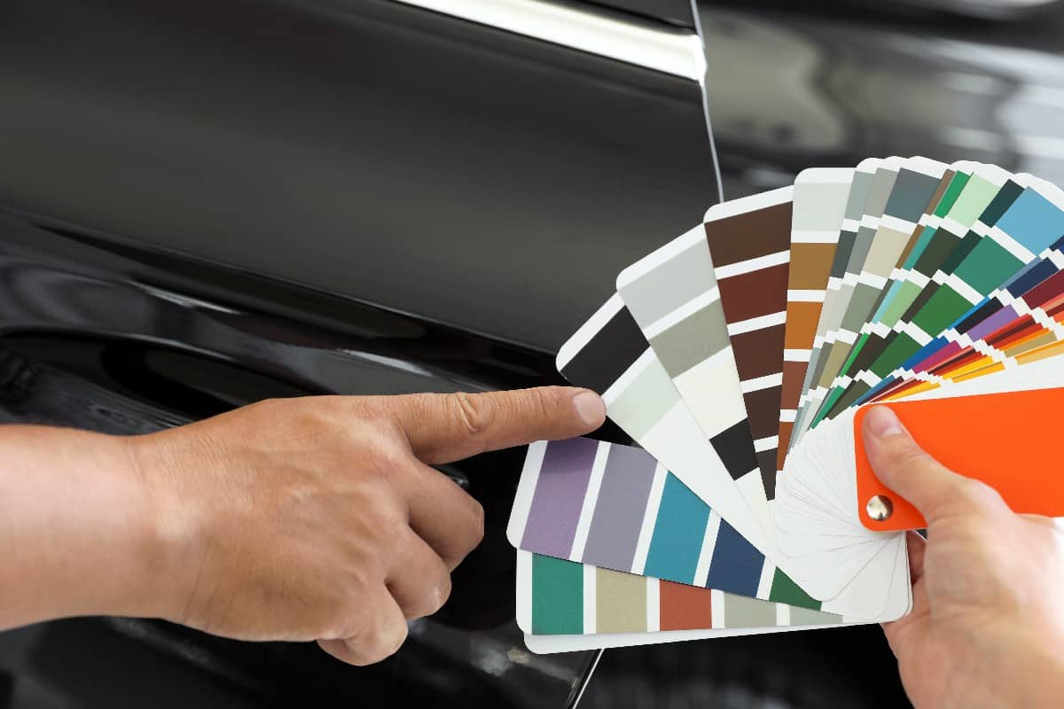 Man choosing color for car painting on palette at service station