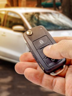 Man presses button on ignition key with immobilizer on the background of the car , How To Use A Remote Starter Switch [Step By Step Guide]