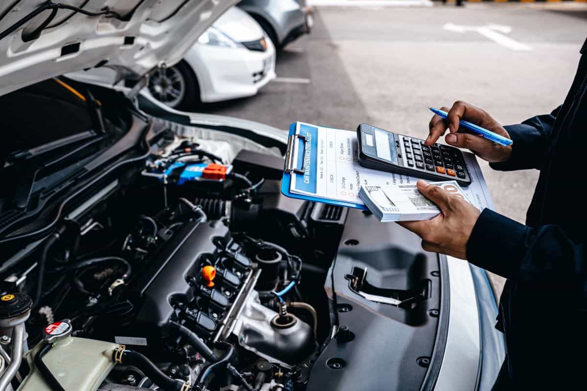 Mechanic calculates the cost of car repairs to customer at garage workshop, Car auto services and maintenance check concept.