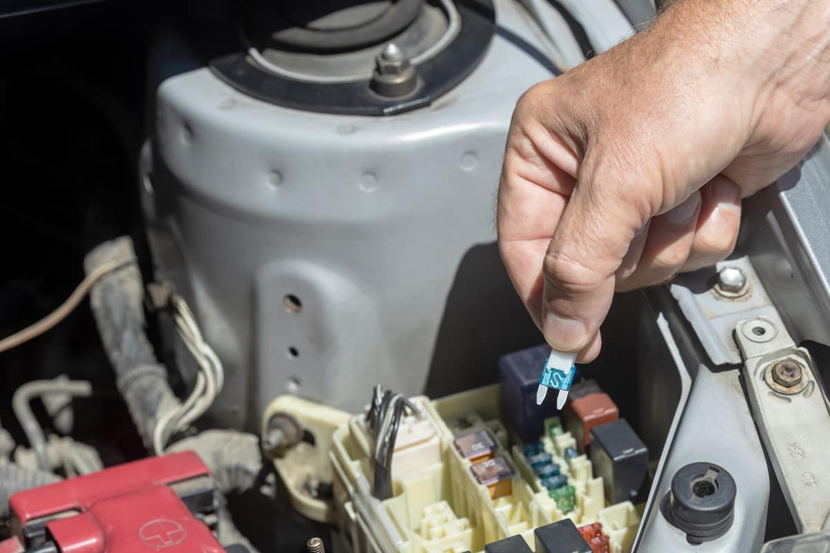 Mechanic pulling out a fuse from the car fuse box