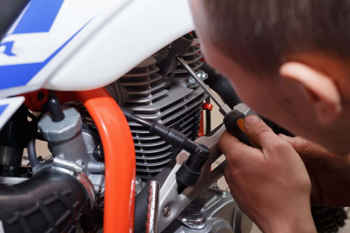 Motorcyclist replaces, checks the glow plug in a motorcycle. Replacing the spark in the repair shop.