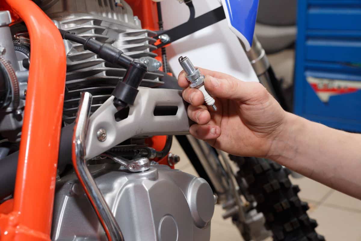 Motorcyclist replaces, checks the glow plug in a motorcycle. Replacing the spark in the repair shop.