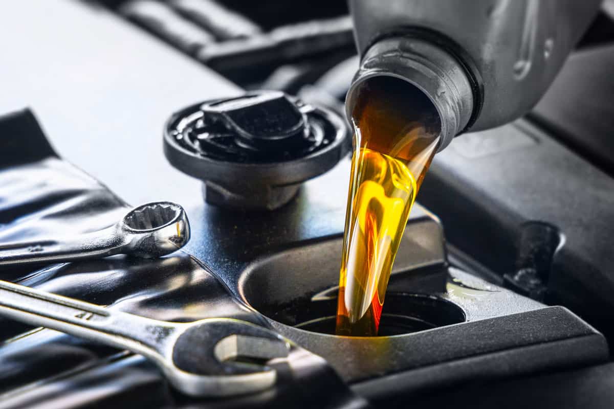 Pouring motor oil for motor vehicles from a gray bottle into the engine, , oil change, auto repair shop, service